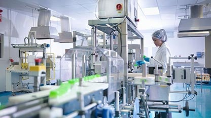 Работник проверява продукти на производствена линия във фармацевтична фабрика
